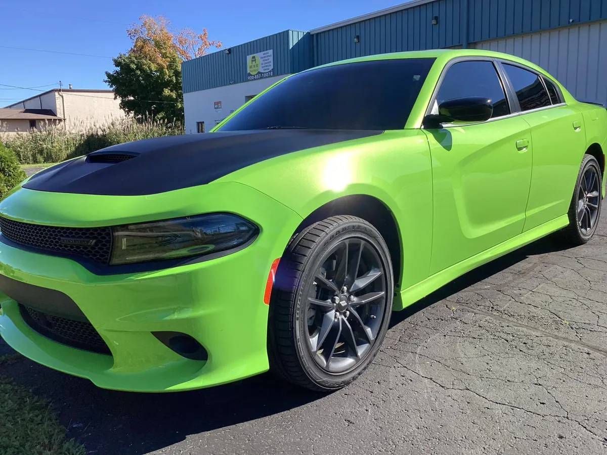 "Bright green Dodge Charger with black hood and tinted windows, customized at GB Enterprises AutoCare in Green Bay, WI. Showcasing professional window tinting and vehicle detailing for enhanced aesthetics and privacy."