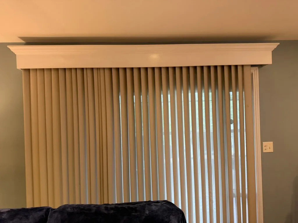 Window with vertical blinds under a white trim cornice board