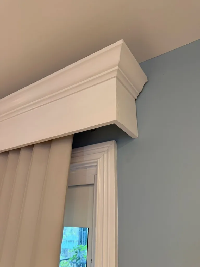 White cornice trim above a window next to a blue painted wall