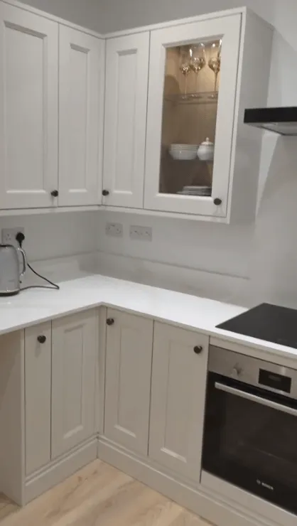 White shaker kitchen installation with glass cabinets and white worktops by Willis Building Services London