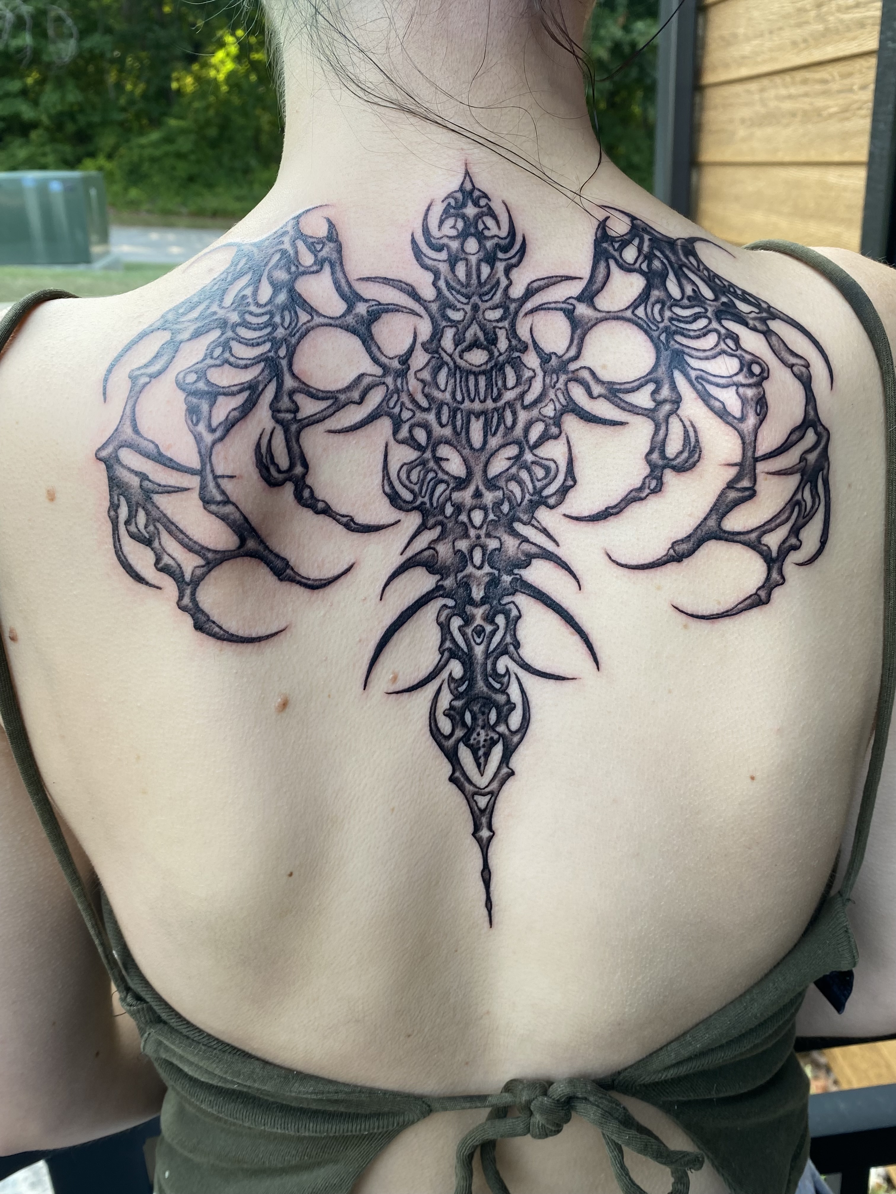 Minimalist linework tattoo of a botanical motif on a man's ankle, captured in a bright, airy space with a neutral backdrop. The style is clean and contemporary. 1:1 aspect ratio.