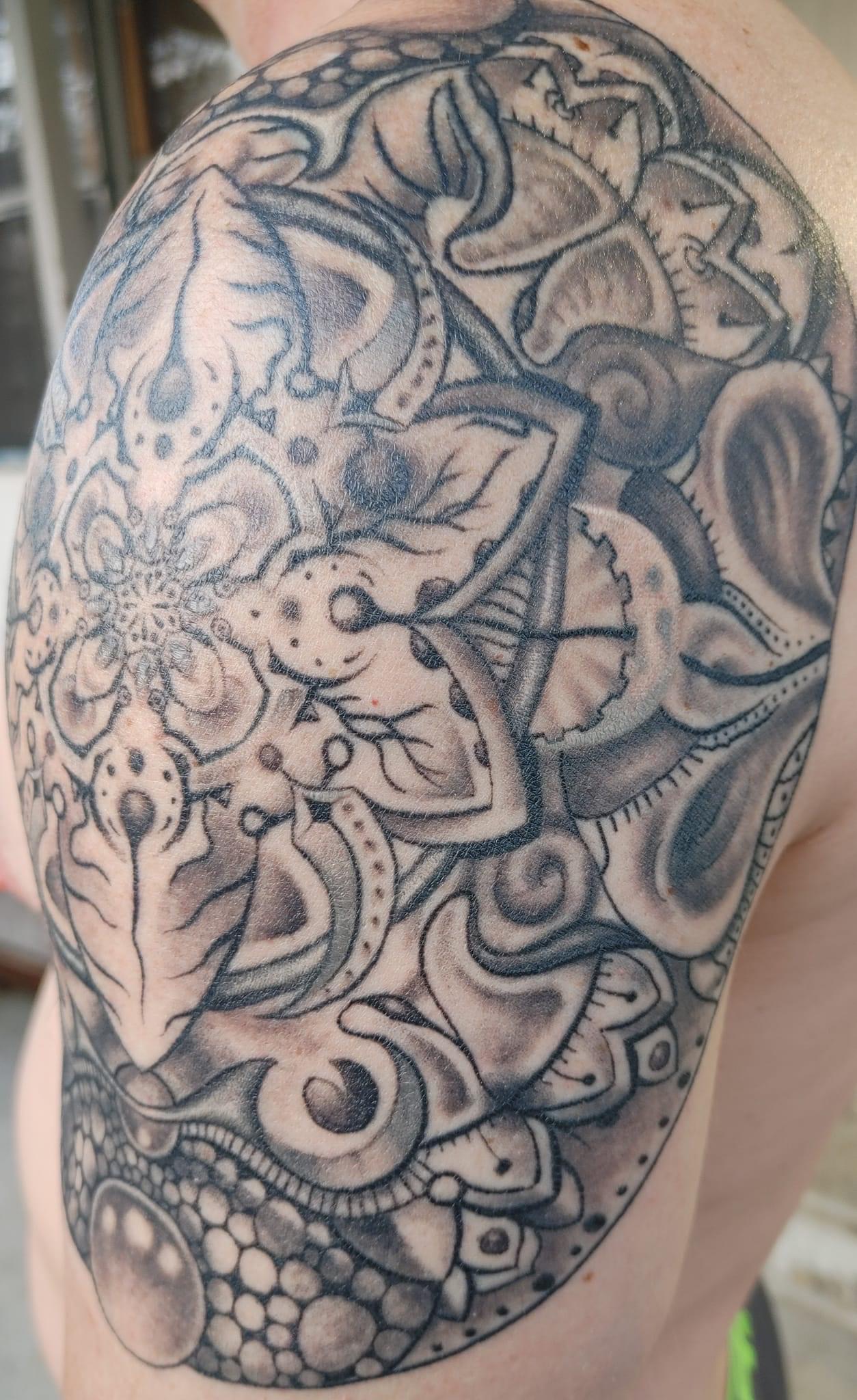 Abstract watercolor tattoo on a woman's shoulder, blending pastel pinks and blues with gold accents. The image is shot in a modern studio with a minimalist background. 1:1 aspect ratio.