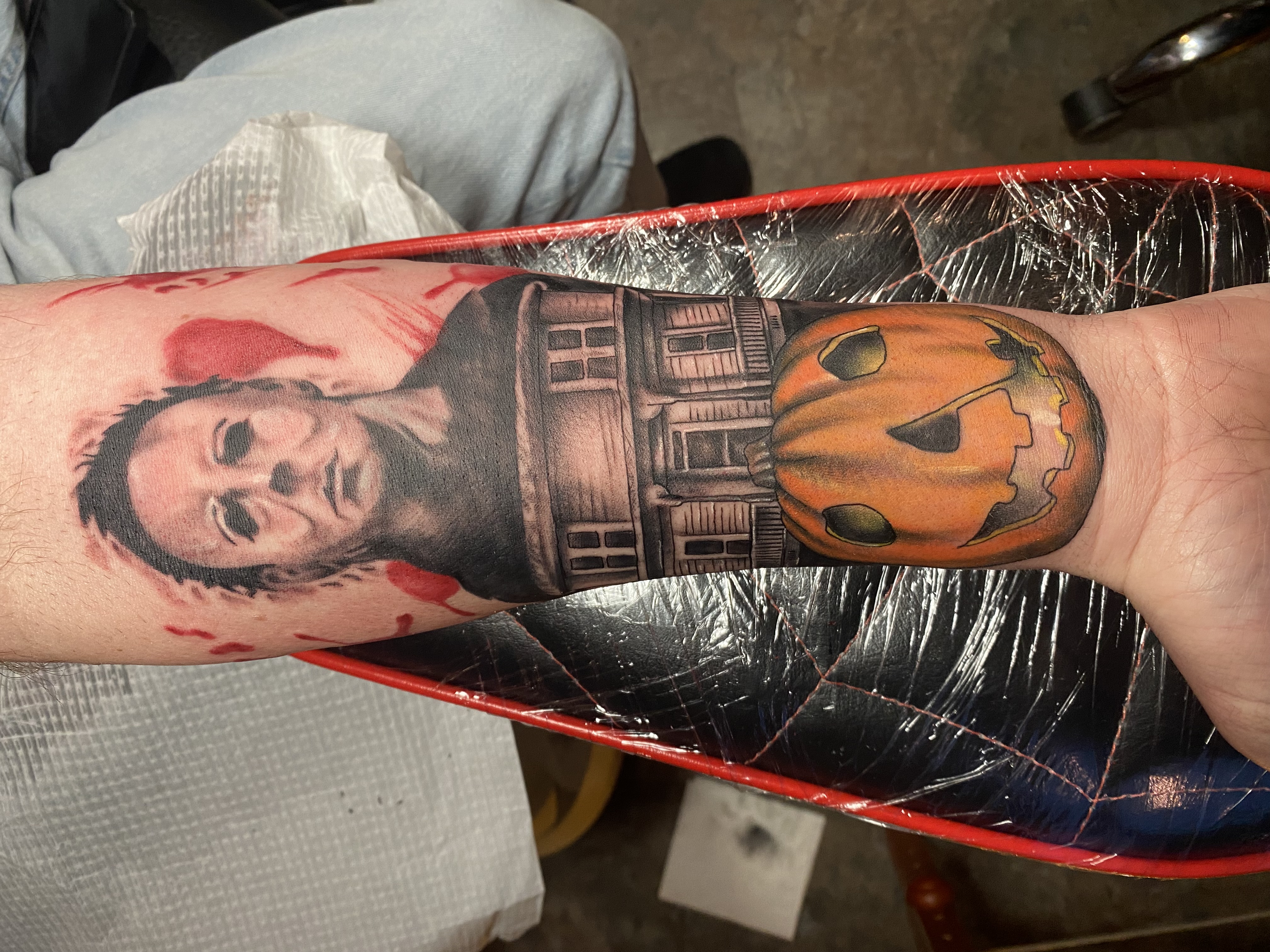 Close-up of a forearm tattoo featuring intricate geometric patterns in black ink, photographed in soft natural light. The background is a blurred studio setting with warm neutral tones. 1:1 aspect ratio.