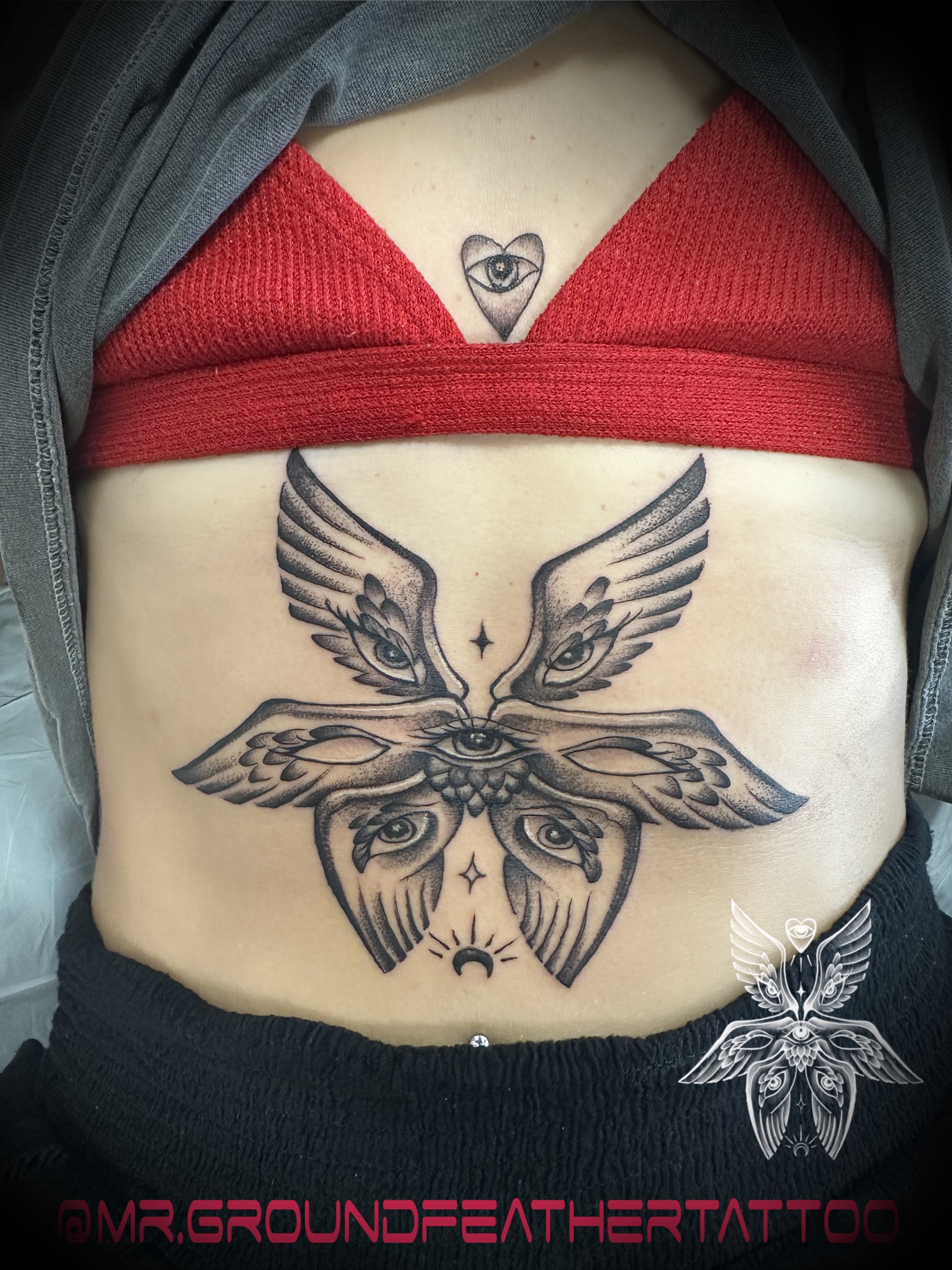 Abstract watercolor tattoo on a woman's shoulder, blending pastel pinks and blues with gold accents. The image is shot in a modern studio with a minimalist background. 1:1 aspect ratio.