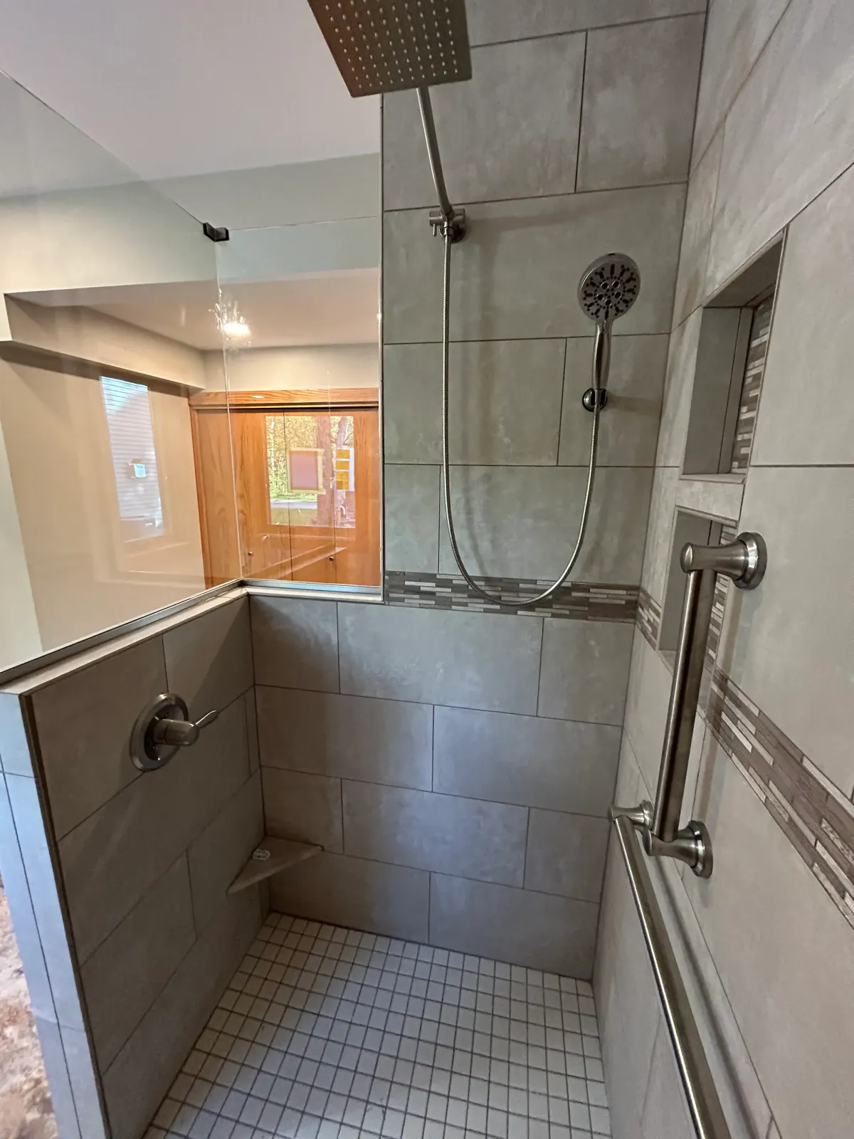 Accessibility-friendly tile shower remodel with grab bars and updated fixtures in West Michigan home.