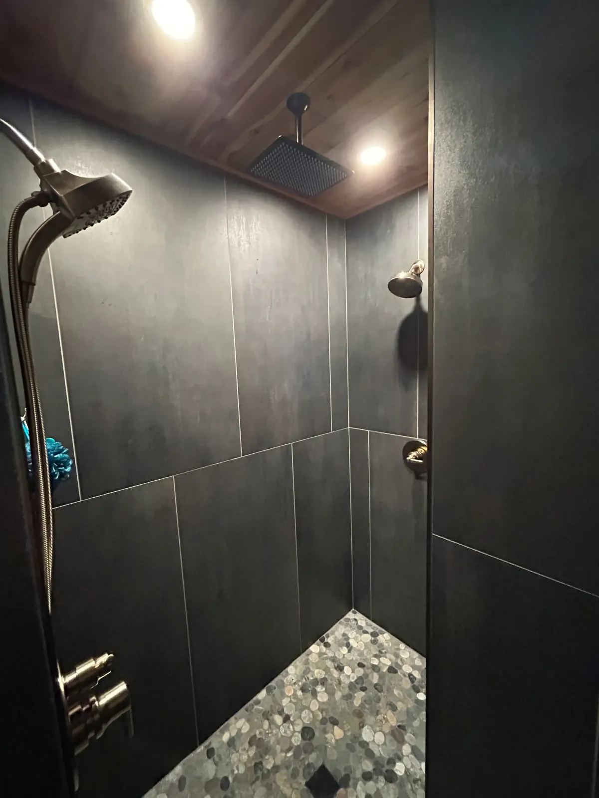 Custom walk-in tile shower with rainhead and dark modern tile installed by Archstone Homes.