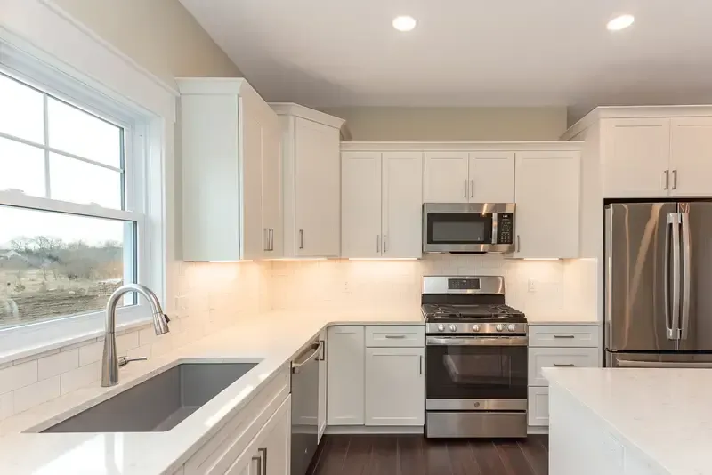 Custom kitchen remodel in West Michigan featuring white shaker cabinets, stainless appliances, and modern lighting by Archstone Homes.
