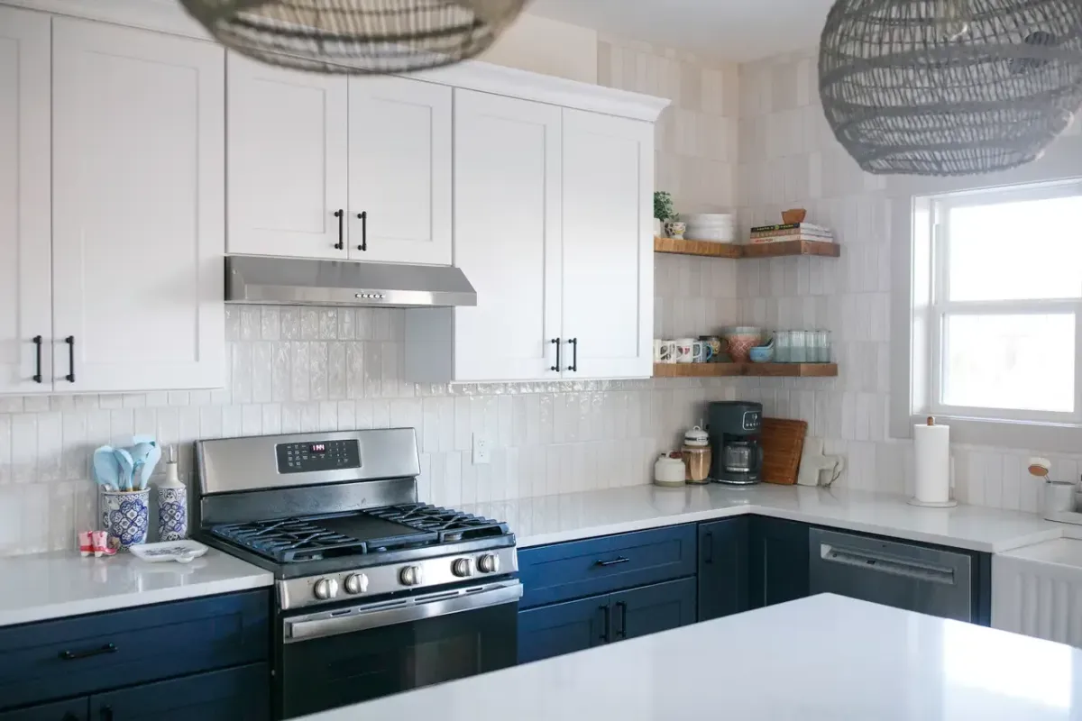 Completed West Michigan kitchen remodel featuring white cabinets, stainless appliances, and modern pendant lighting by Archstone Homes.
