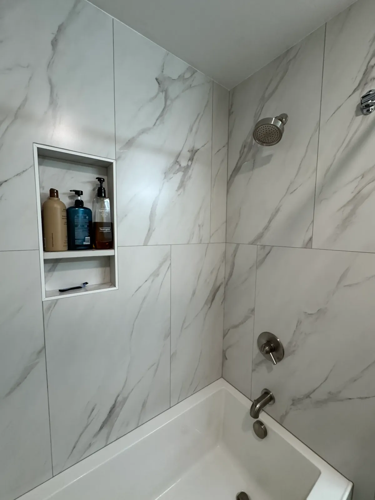 Updated bathroom shower with niche storage and contemporary tile work in West Michigan home.