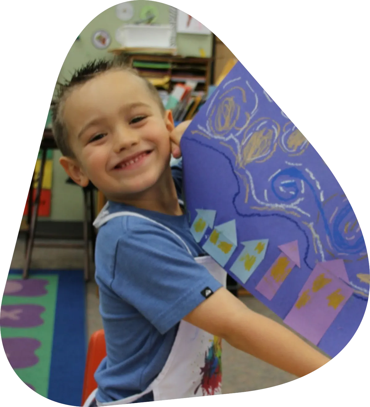 Smiling child holding colorful artwork in a classroom, showcasing creativity and engagement in art education.