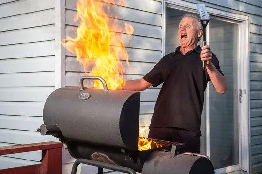 grayscale photo of man standing near gas grill