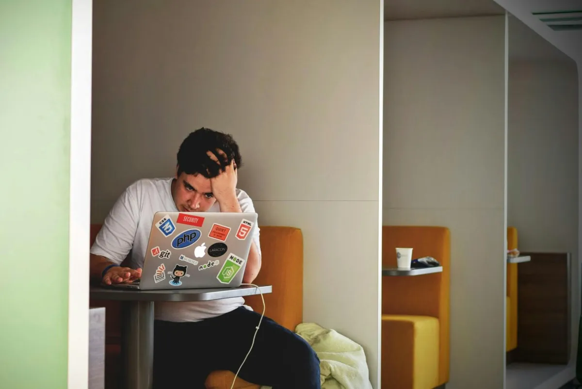 Man sitting with head in his hands at a laptop