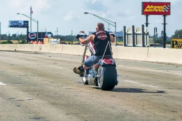 man sitting on ground beside parked silver cruiser motorcycle