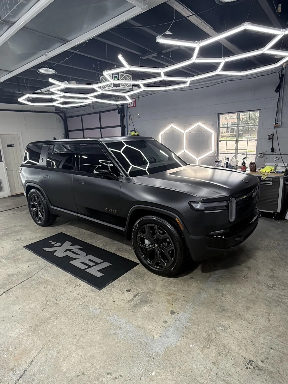 Tesla undergoing XPEL paint protection film installation in climate-controlled studio.