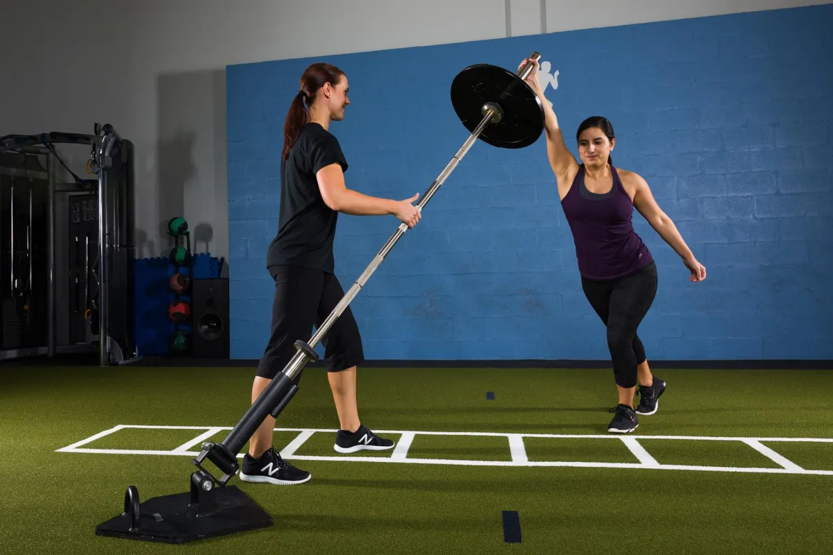 Physical therapist coaching an adult exercise client on the landmine.
