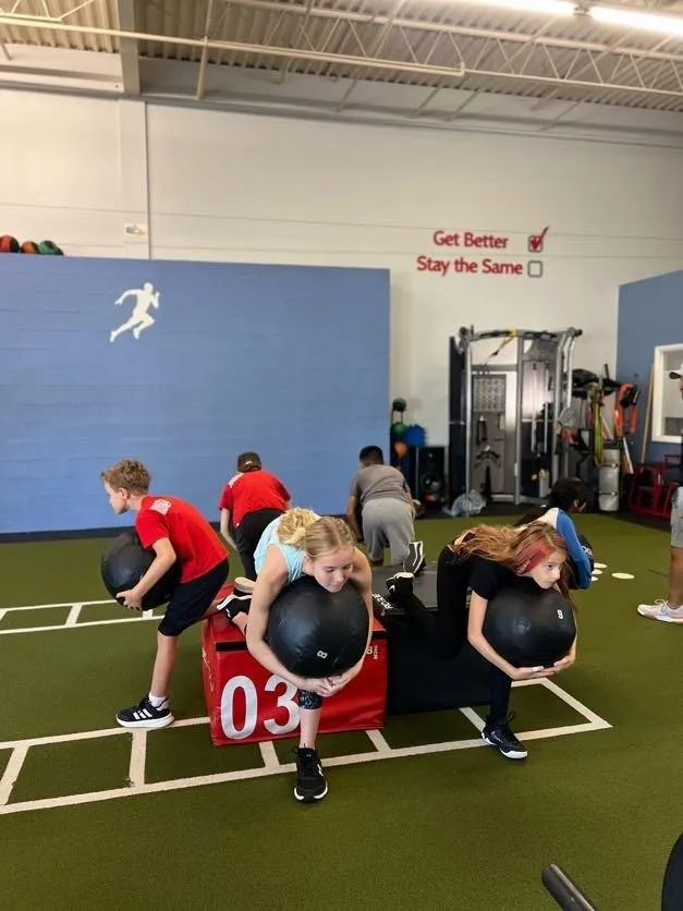 Young boys and girls holding medicine balls and exercising