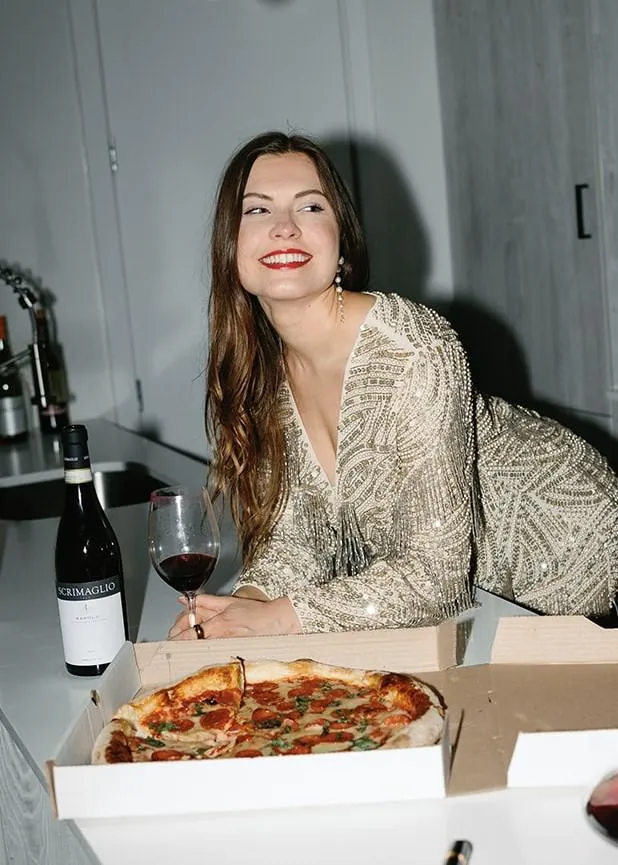 woman-gold-dress-drinking-wine-with-pizza