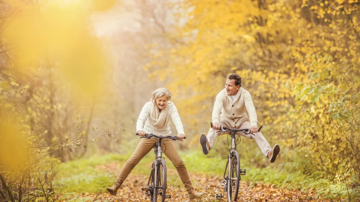 an older couple cycling through the woods