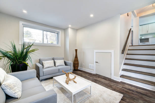 Staged living area with seating arrangement beside staircase and natural light