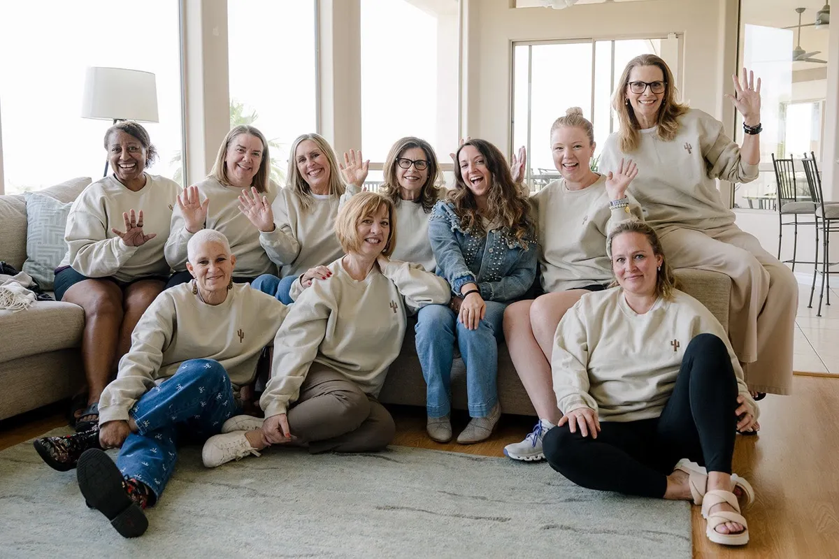 A group of cheerful women sitting together on a white couch and chairs in a bright, modern room.