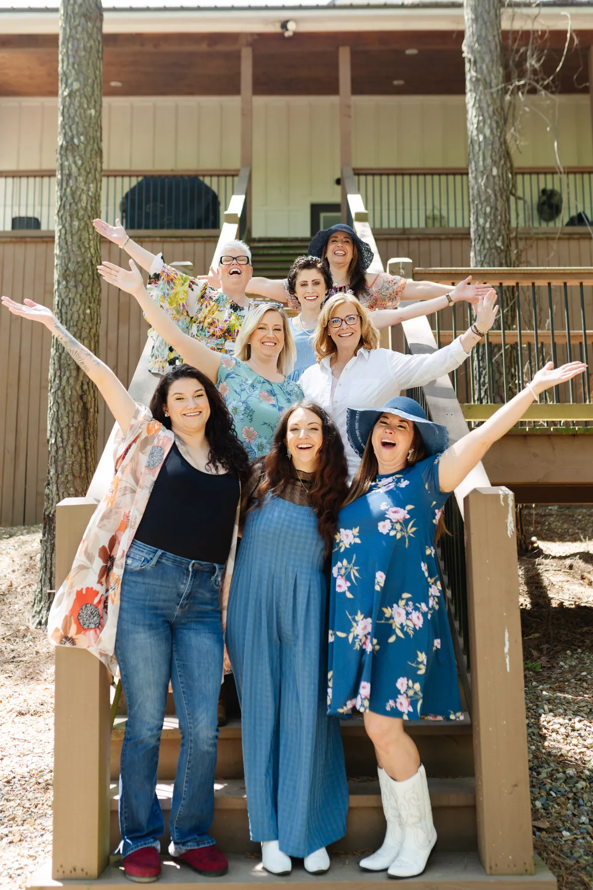 Four smiling women outdoors, holding cameras and wearing casual stylish clothing.