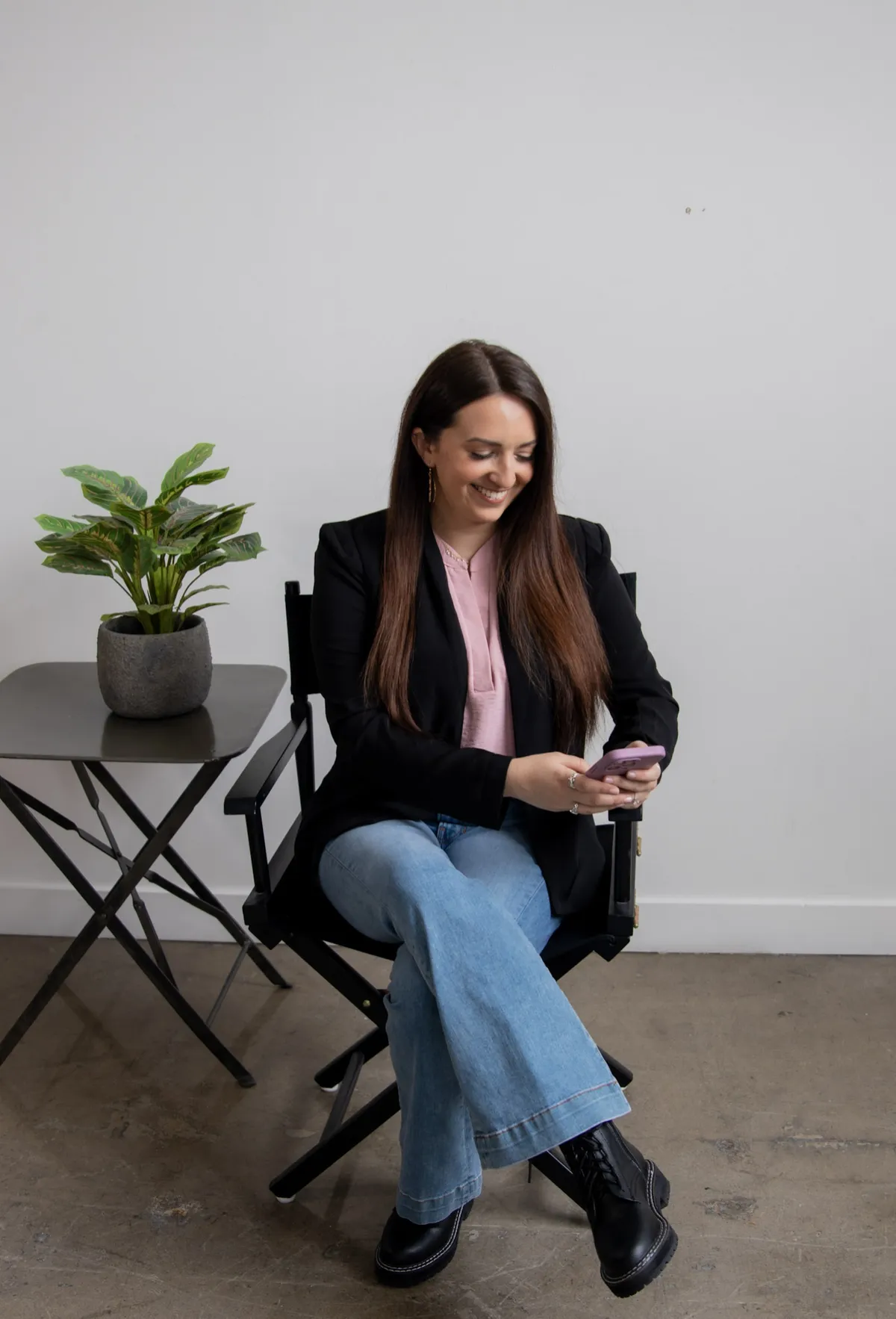 Woman in blue top sitting casually, looking at a laptop in her lap.