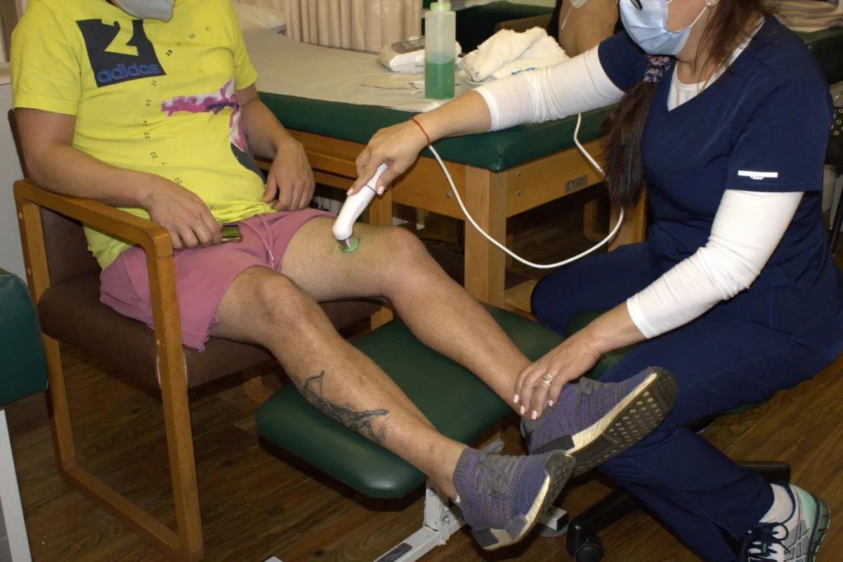 Therapist performing therapeutic ultrasound therapy to a patient's left knee
