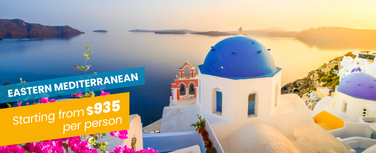 man in green jacket standing on rock formation near body of water