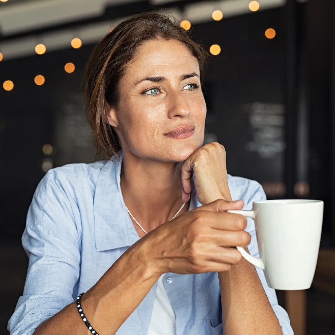 Woman drinking coffee thinking about holistic wellness coaching