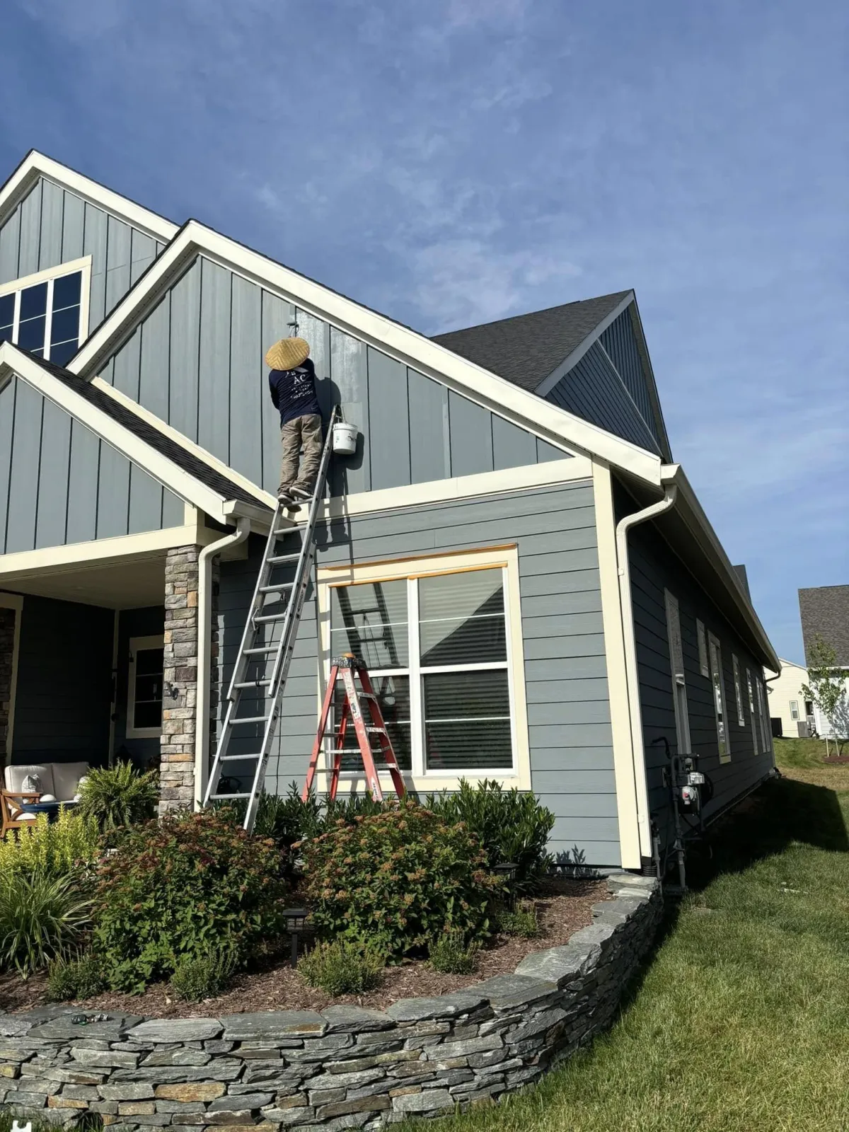 AC Solutions & More team member painting exterior siding on a home in Winchester, VA