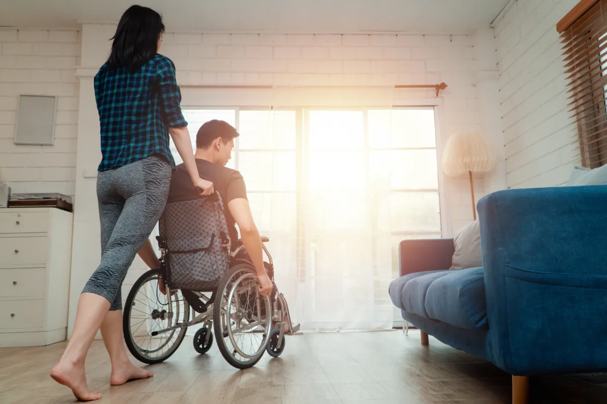 Wife assisting husband in wheelchair currently on disability insurance