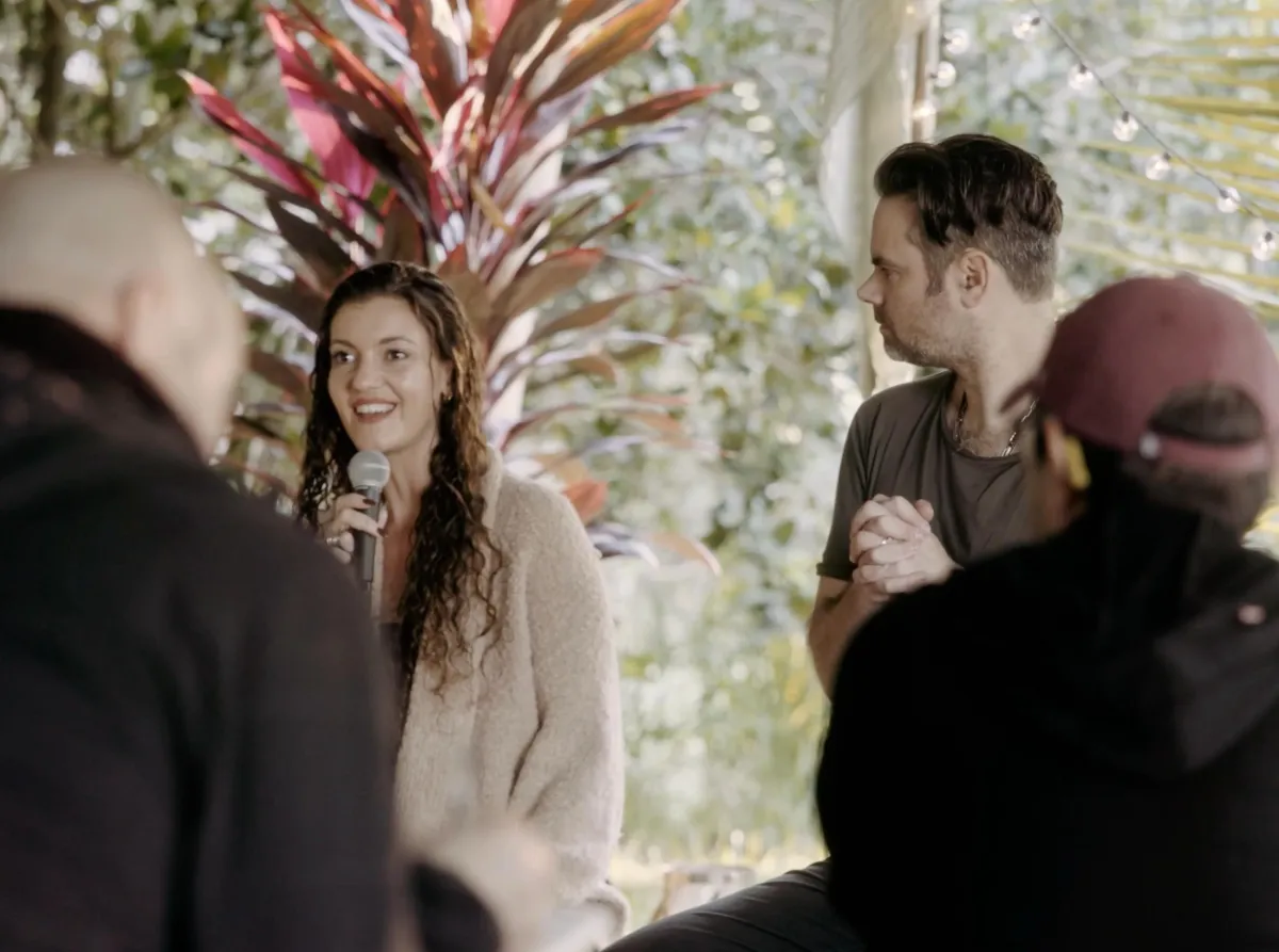 A woman speaks into a microphone during an outdoor gathering