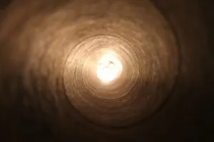 Looking along a dark tunnel towards a bright light