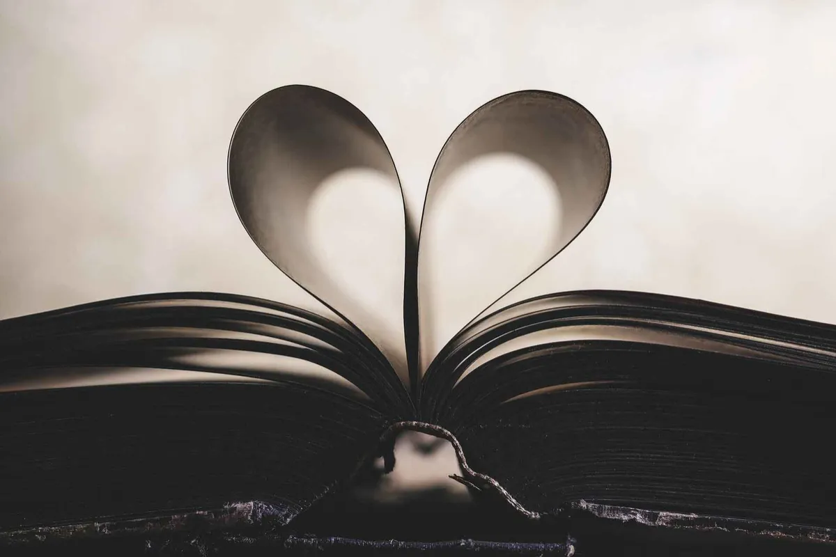 An open book with its pages folded into a heart shape