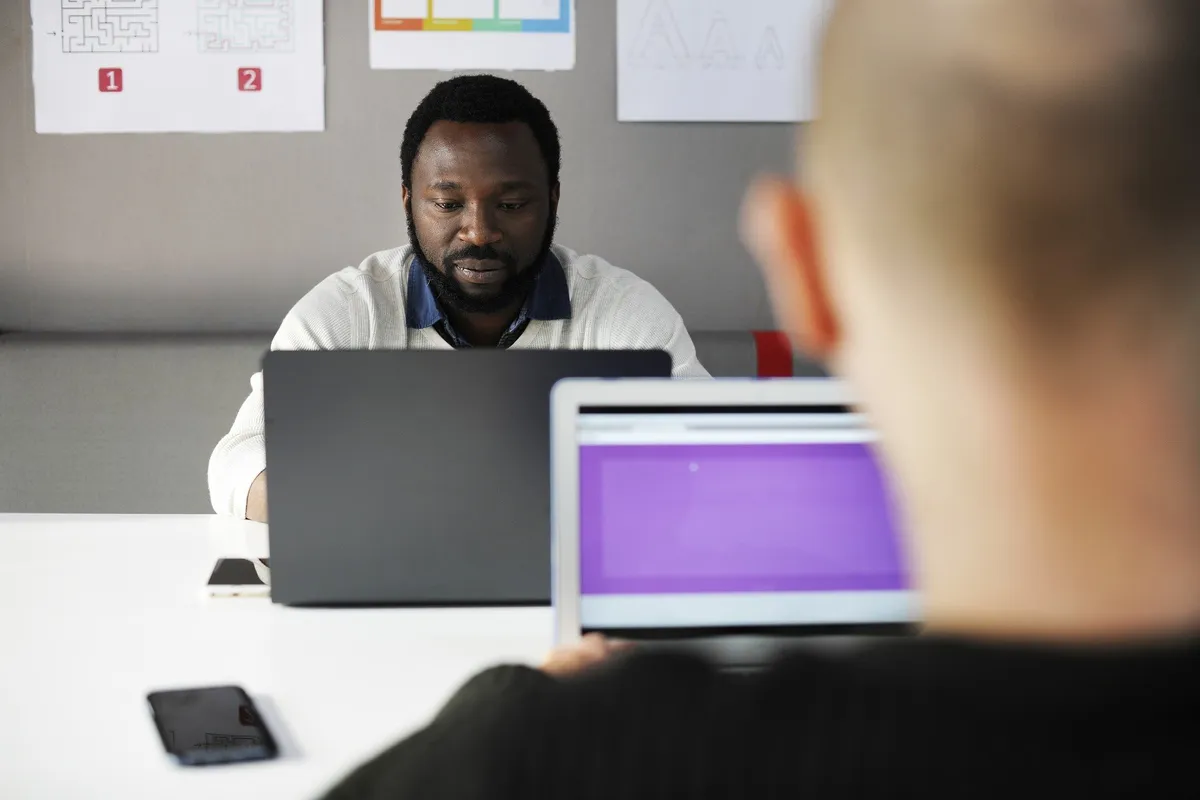 A man working at a laptop at a white desk