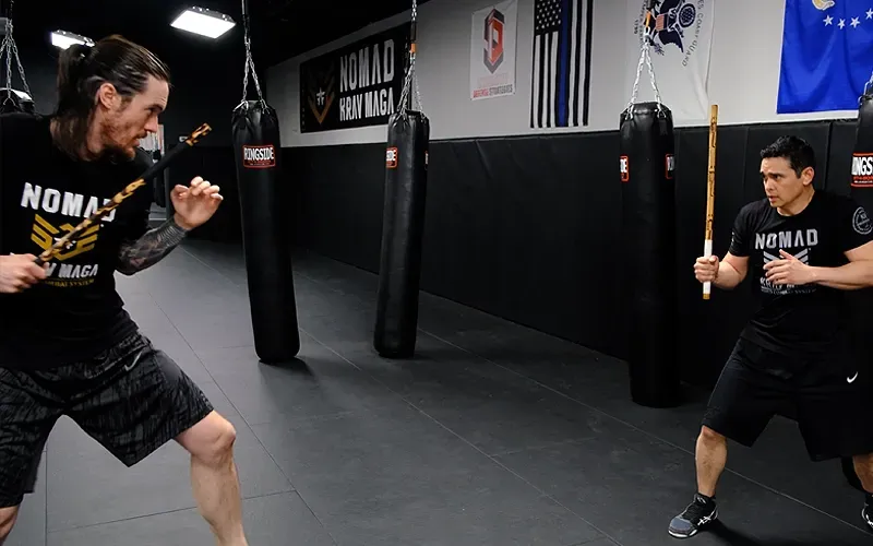 Adult students practicing stick fighting and weapons-based self-defense training at Nomad Mixed Combat HQ in Fort Smith, Arkansas.