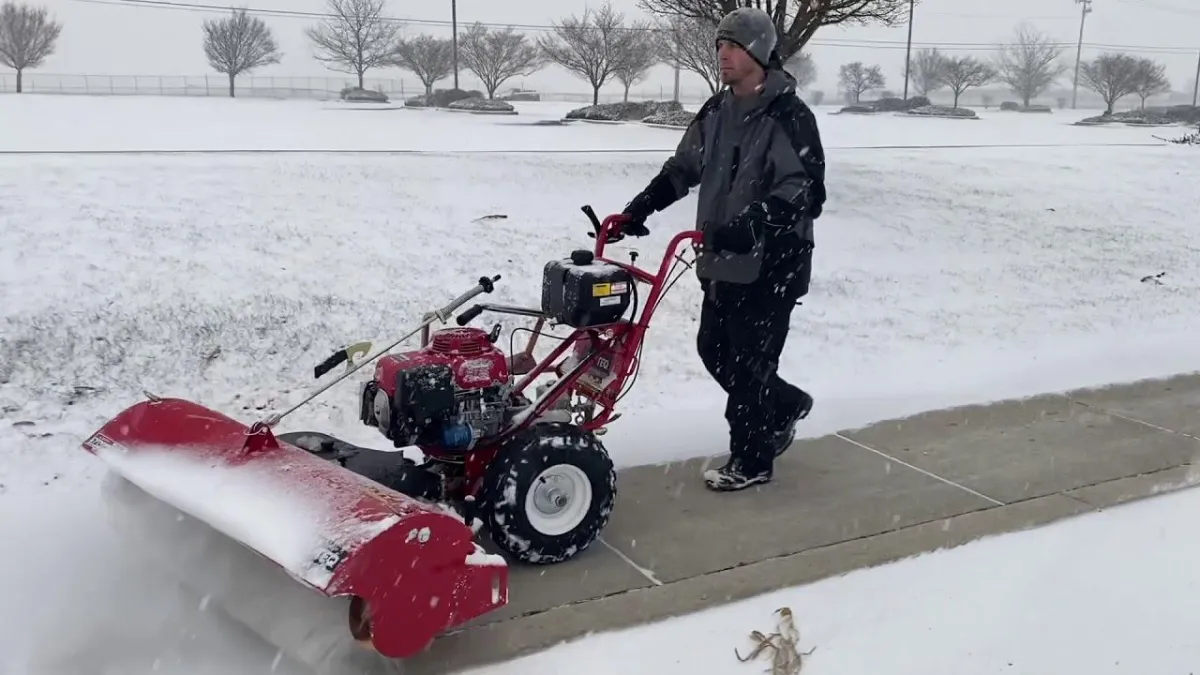 Snow removal crew working on clearing snow from a city sidewalk.