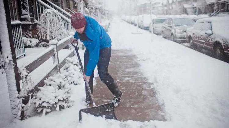 Shoveling snow from a driveway to ensure safe access during winter weather.
