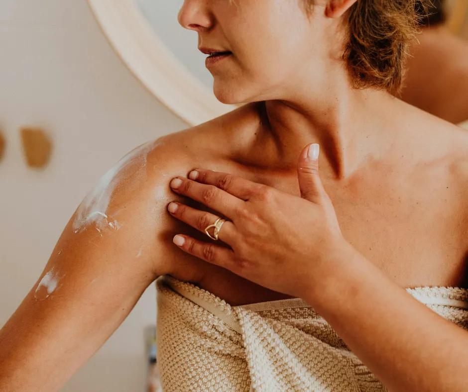 Woman applying soothing cream to her shoulder after NeoGen PSR treatment, showing gentle skin care and post-treatment healing.