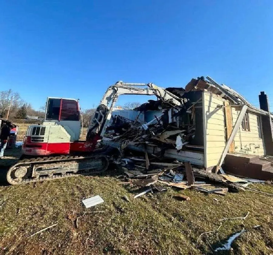 Yellow excavator arm and bucket casting shadow on ground