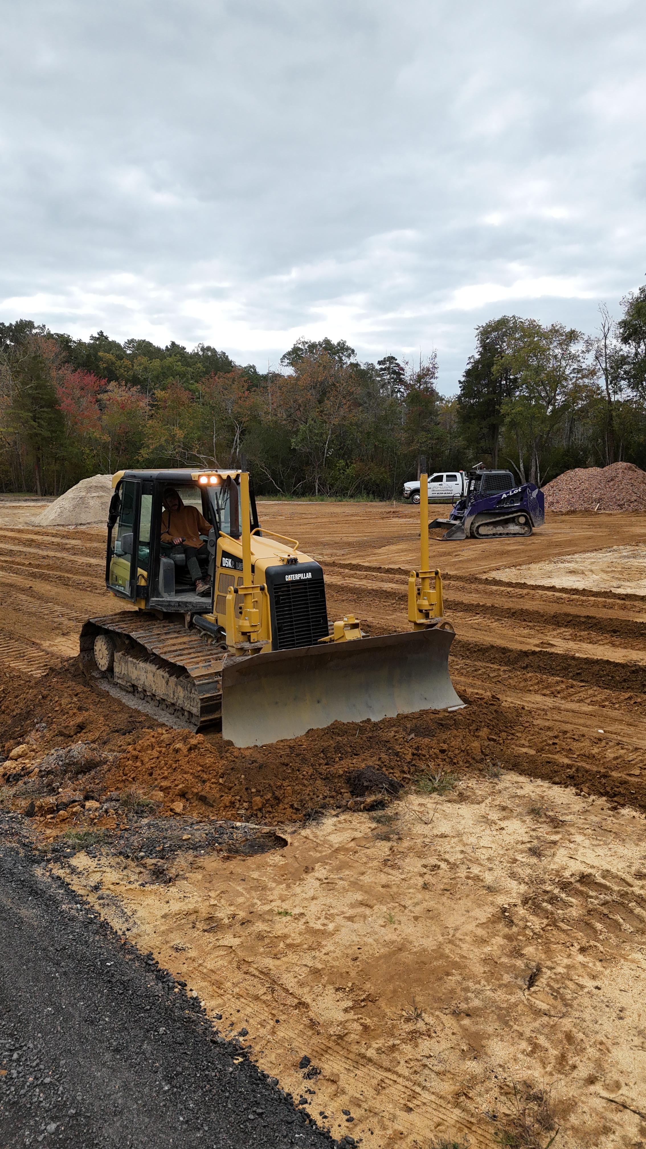 Yellow excavator arm and bucket casting shadow on ground