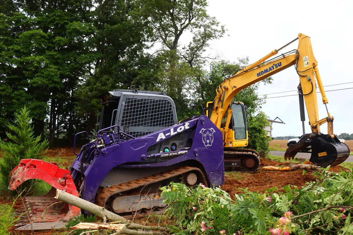 Yellow excavator arm and bucket casting shadow on ground