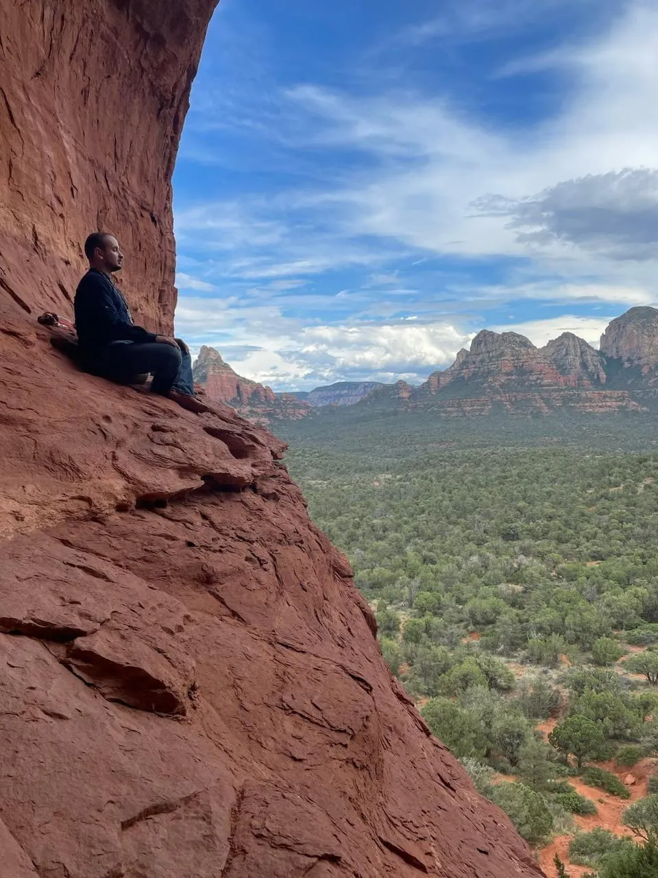 Photo of a male owner, who is a Reiki master, shamanic practitioner, and Kambo facilitator, taken at the Birthing Canal in Sedona, Arizona. He is depicted in natural outdoor surroundings, characteristic of the red rock formations of Sedona, enhancing the spiritual and healing ambiance. His attire is casual yet respectful, suitable for a shamanic and Reiki practitioner, and he exudes an aura of calmness and wisdom. The unique landscape of the Birthing Canal provides a powerful and symbolic backdrop, reflecting his deep connection to nature and spiritual practices. His pose and expression convey a sense of groundedness and profound knowledge in his diverse healing modalities.
