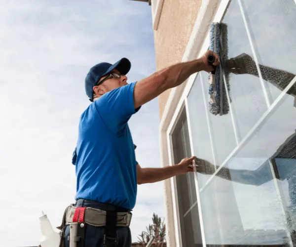 Window cleaner in Spokane on ladder washing second-story residential window