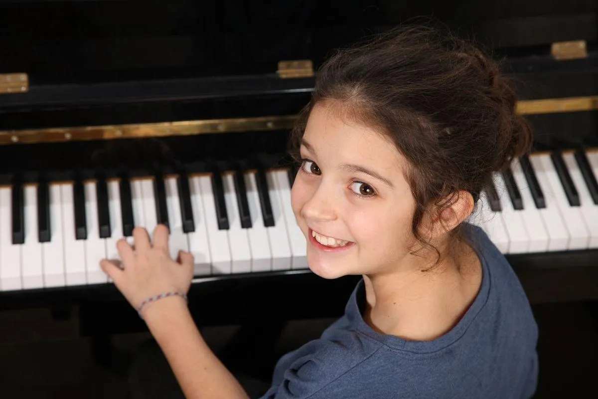Smiling child playing piano during music lesson