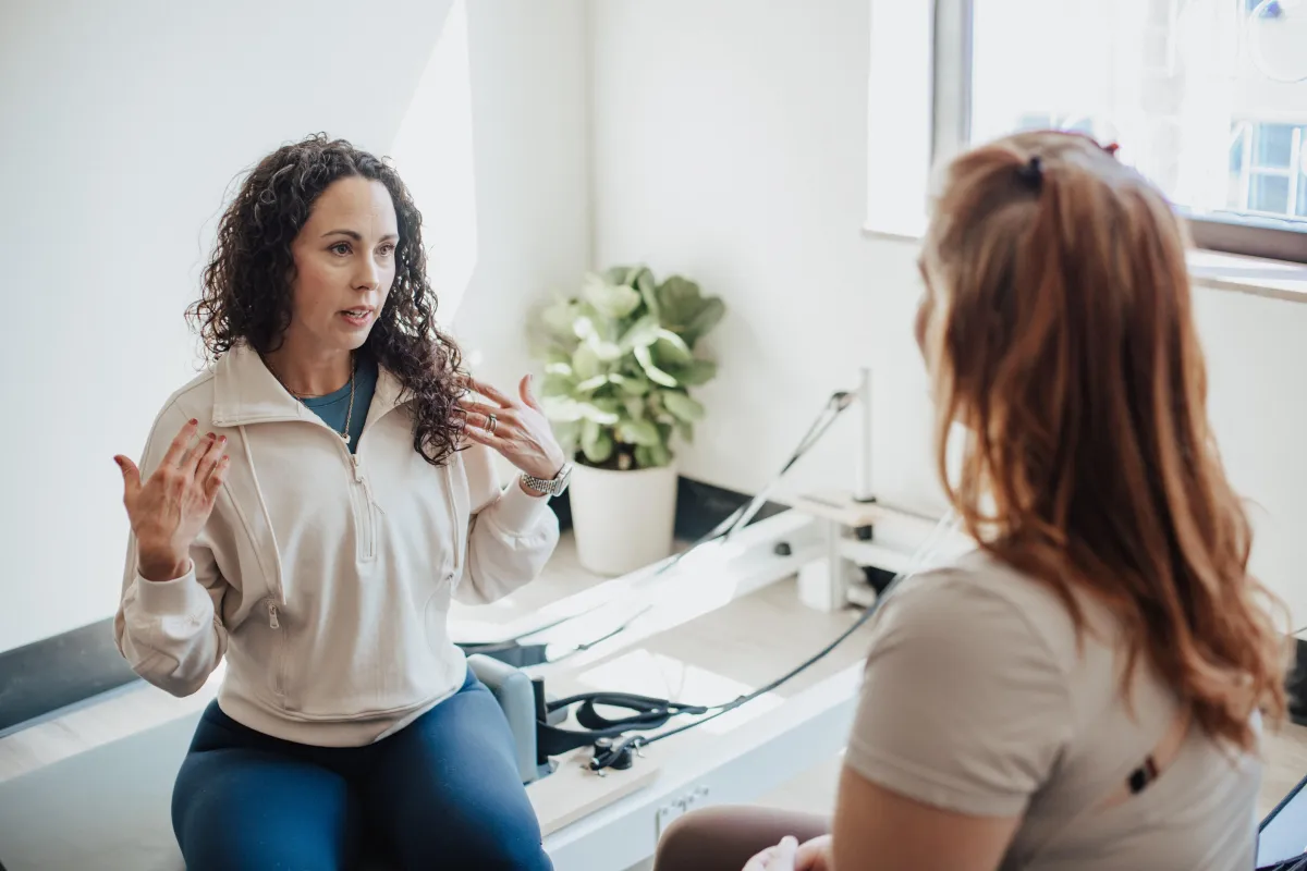 two women talking about health sitting on reformers