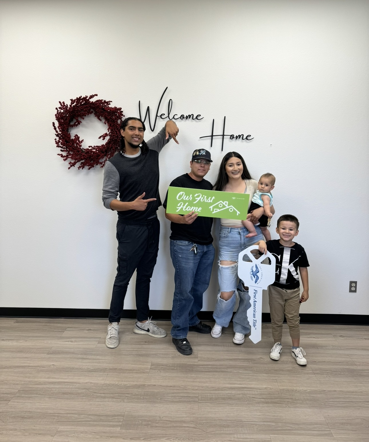 A family celebrating a first home with a sign and closing key