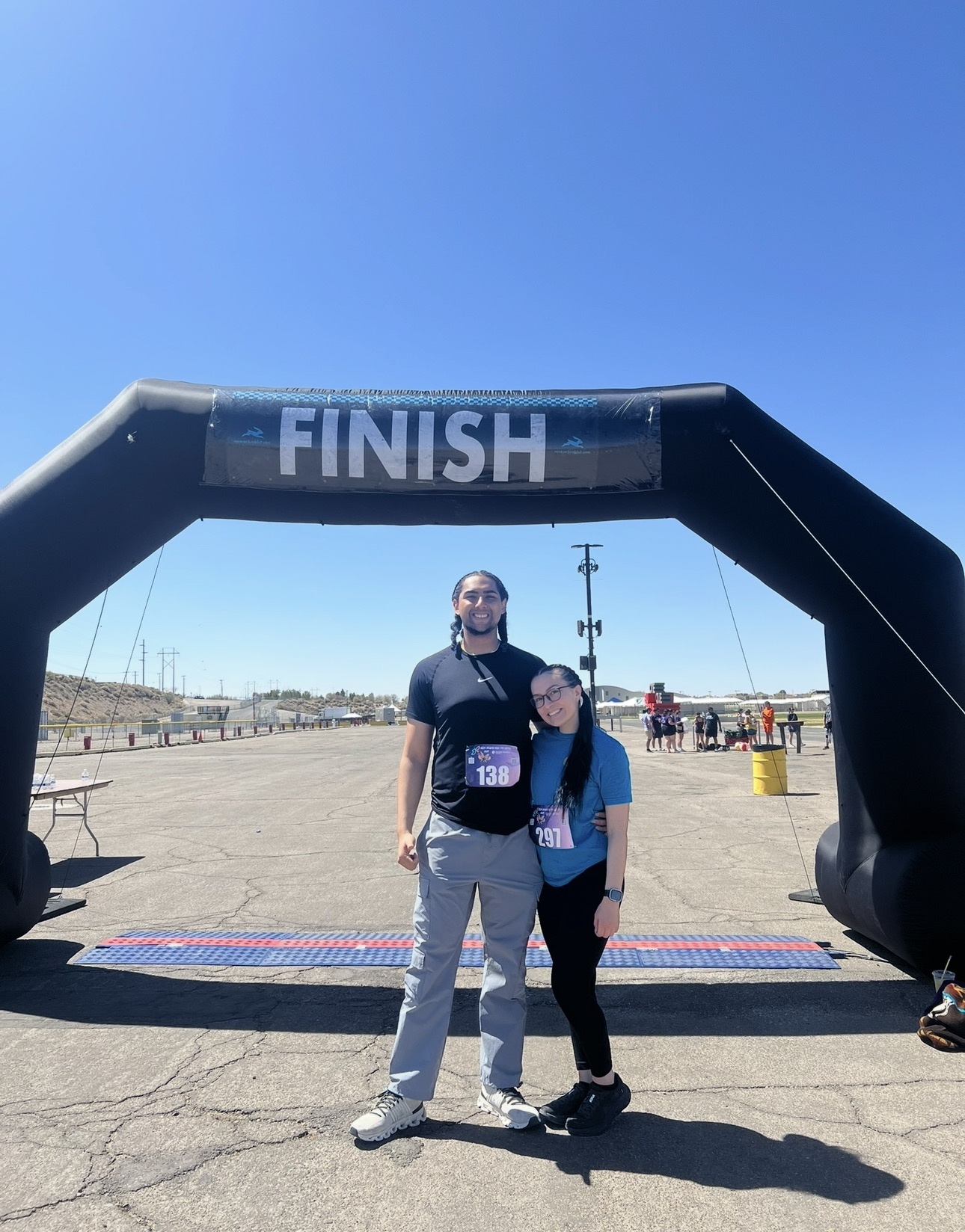 Two runners standing together beneath a finish-line arch