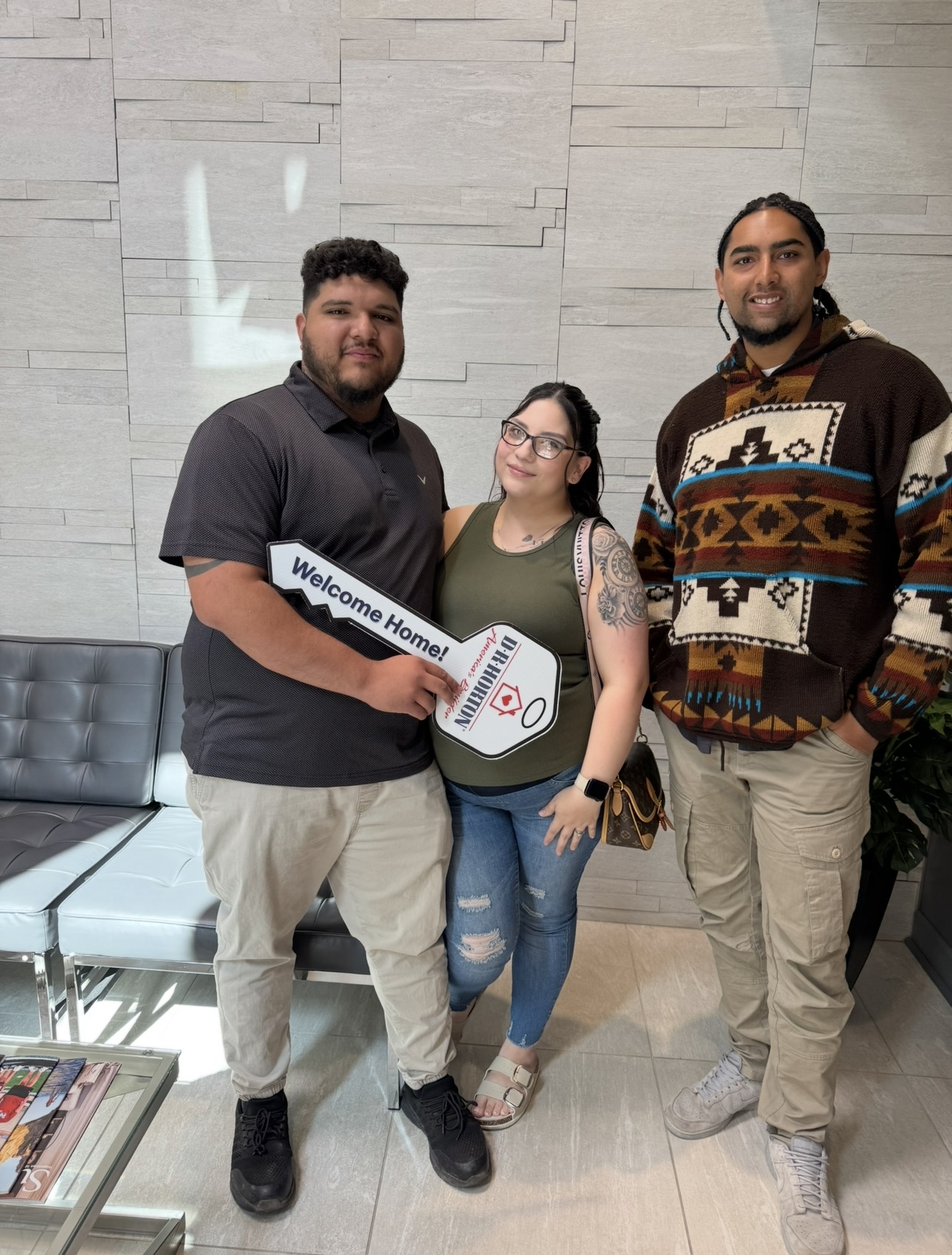 Three people celebrating with a welcome-home key