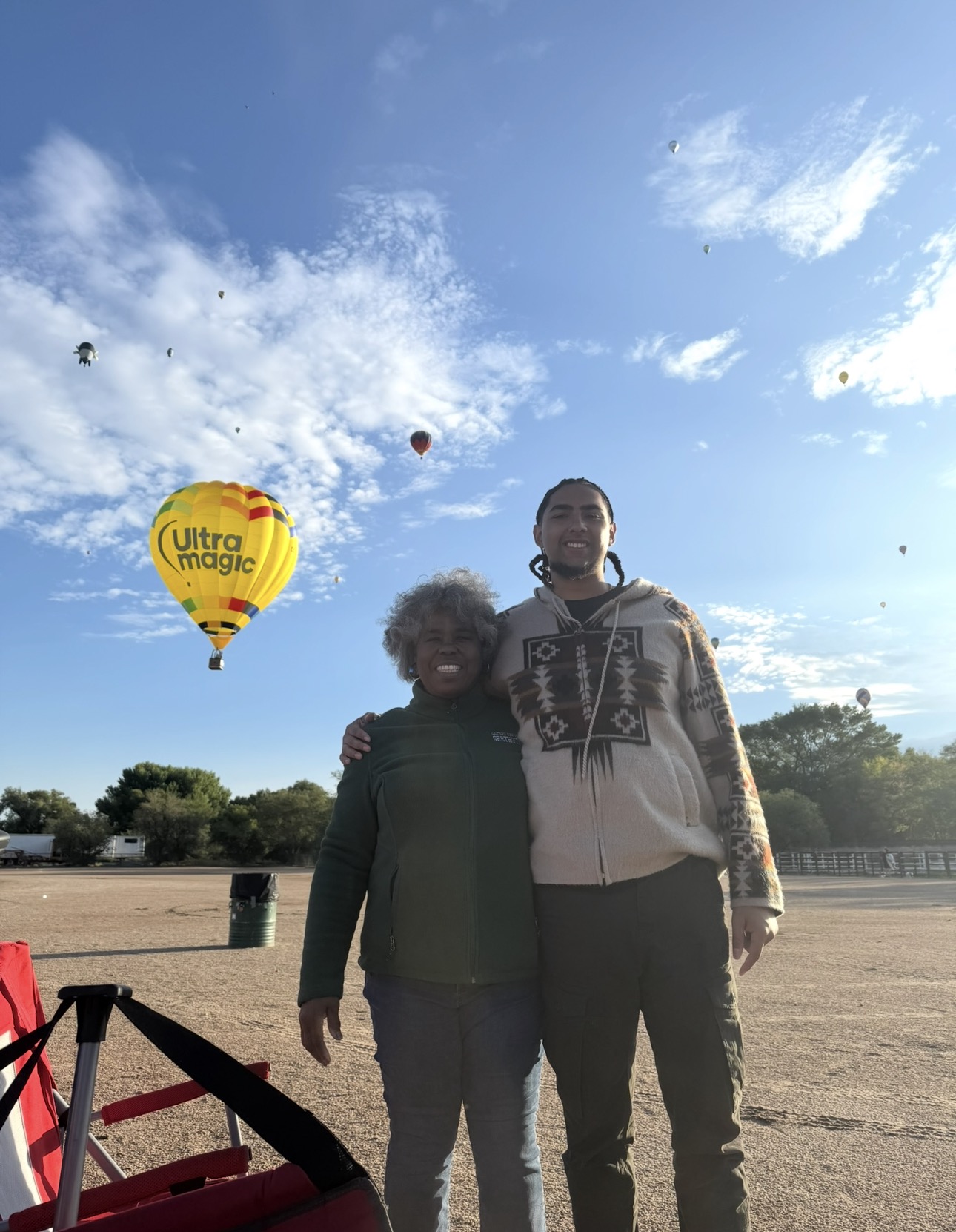 Two people standing beneath hot-air balloons at an outdoor event